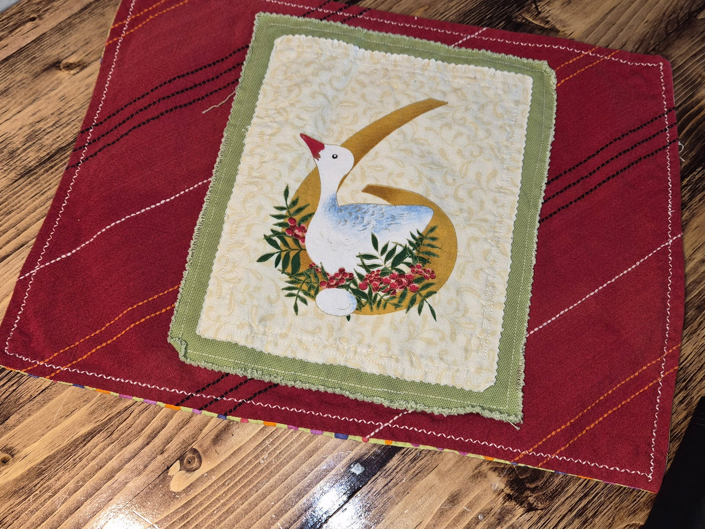 Quilted square with a goose design on a red fabric background