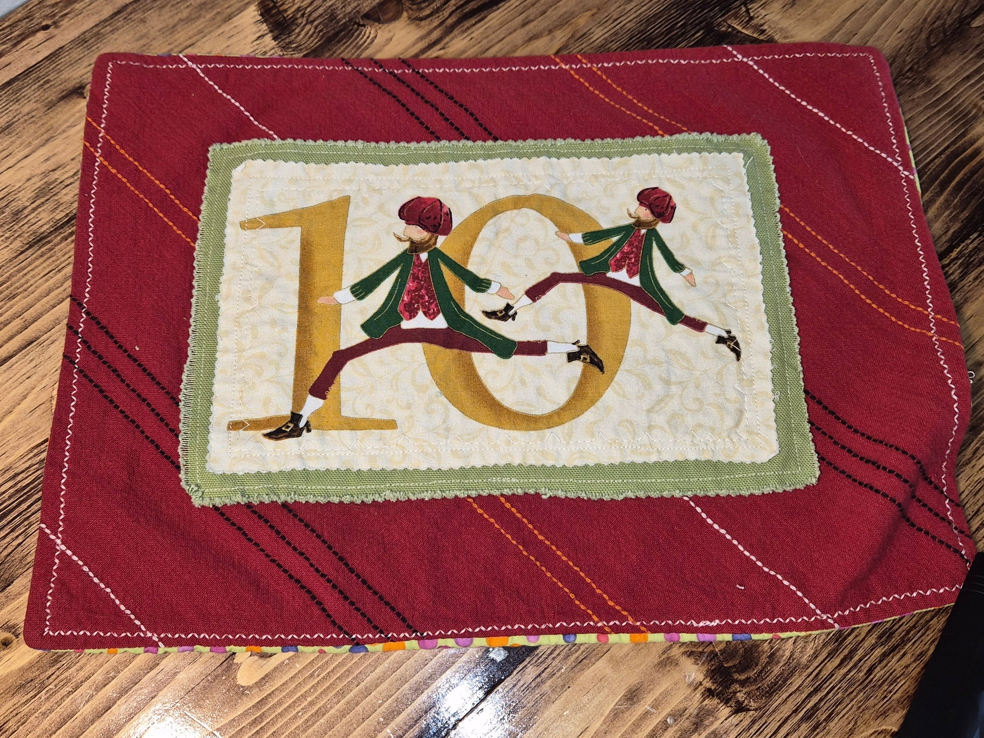Decorative item with number '10' and two figures on a red fabric background
