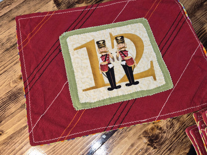 Red quilted fabric with a decorative square featuring two nutcrackers and the letter 'D'.