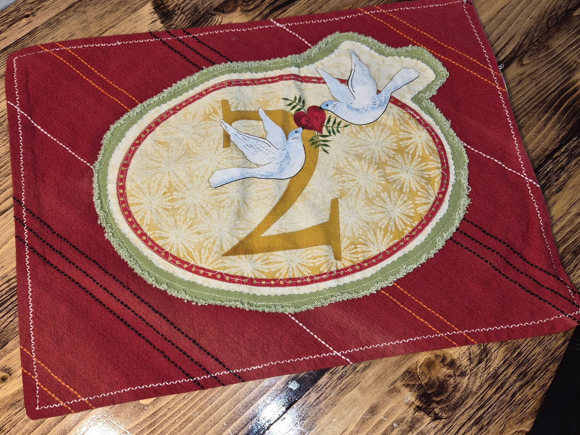 Decorative red fabric with a central design featuring two doves and the number '2'.