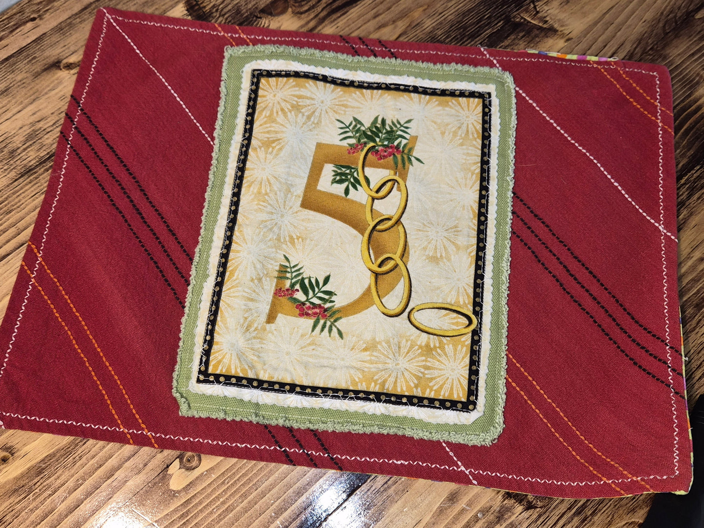 Decorative 5 golden rings on a red fabric background