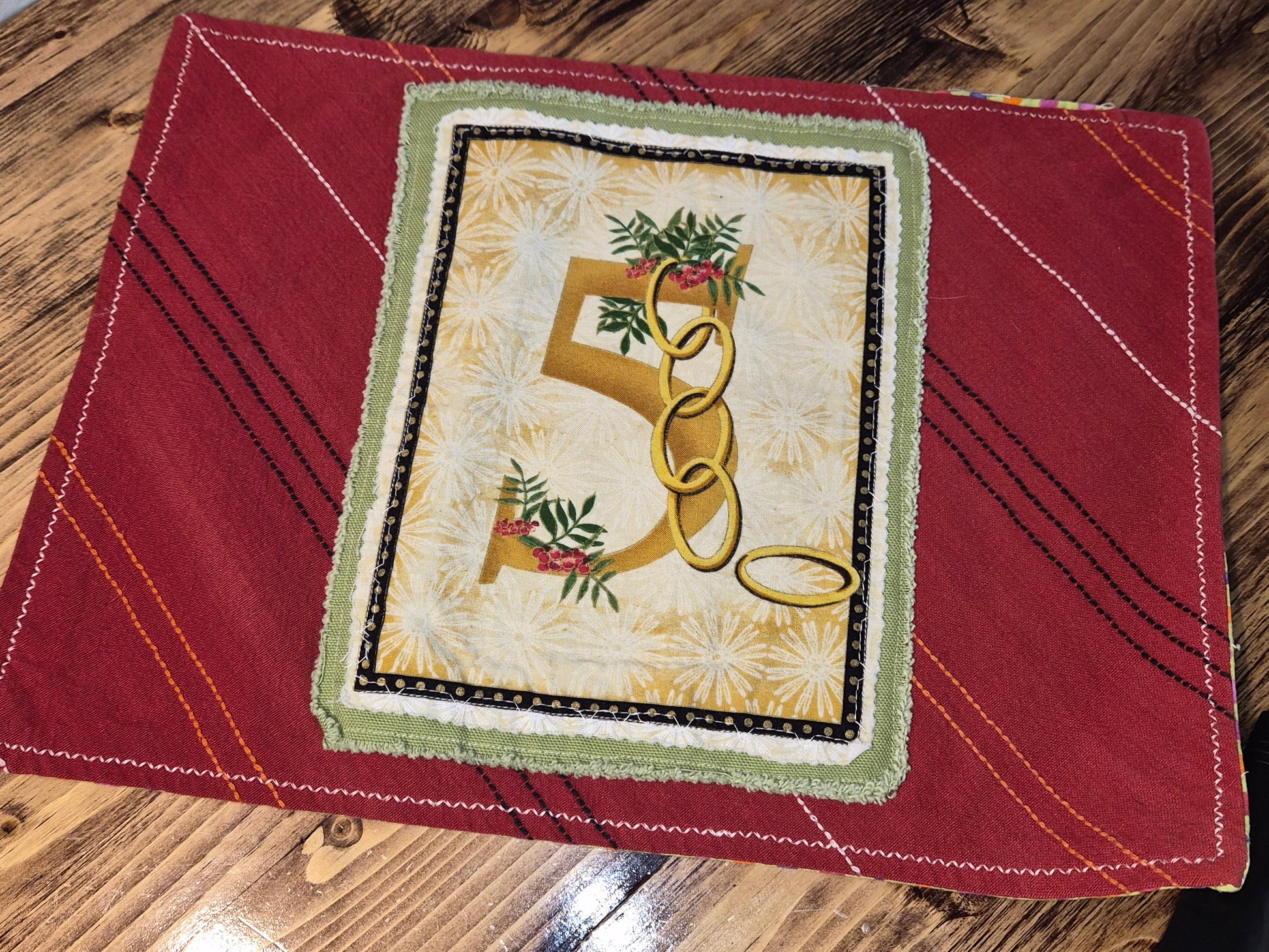 Decorative 5 golden rings on a red fabric background