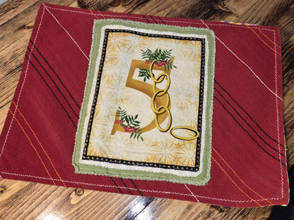 Decorative 5 golden rings on a red fabric background