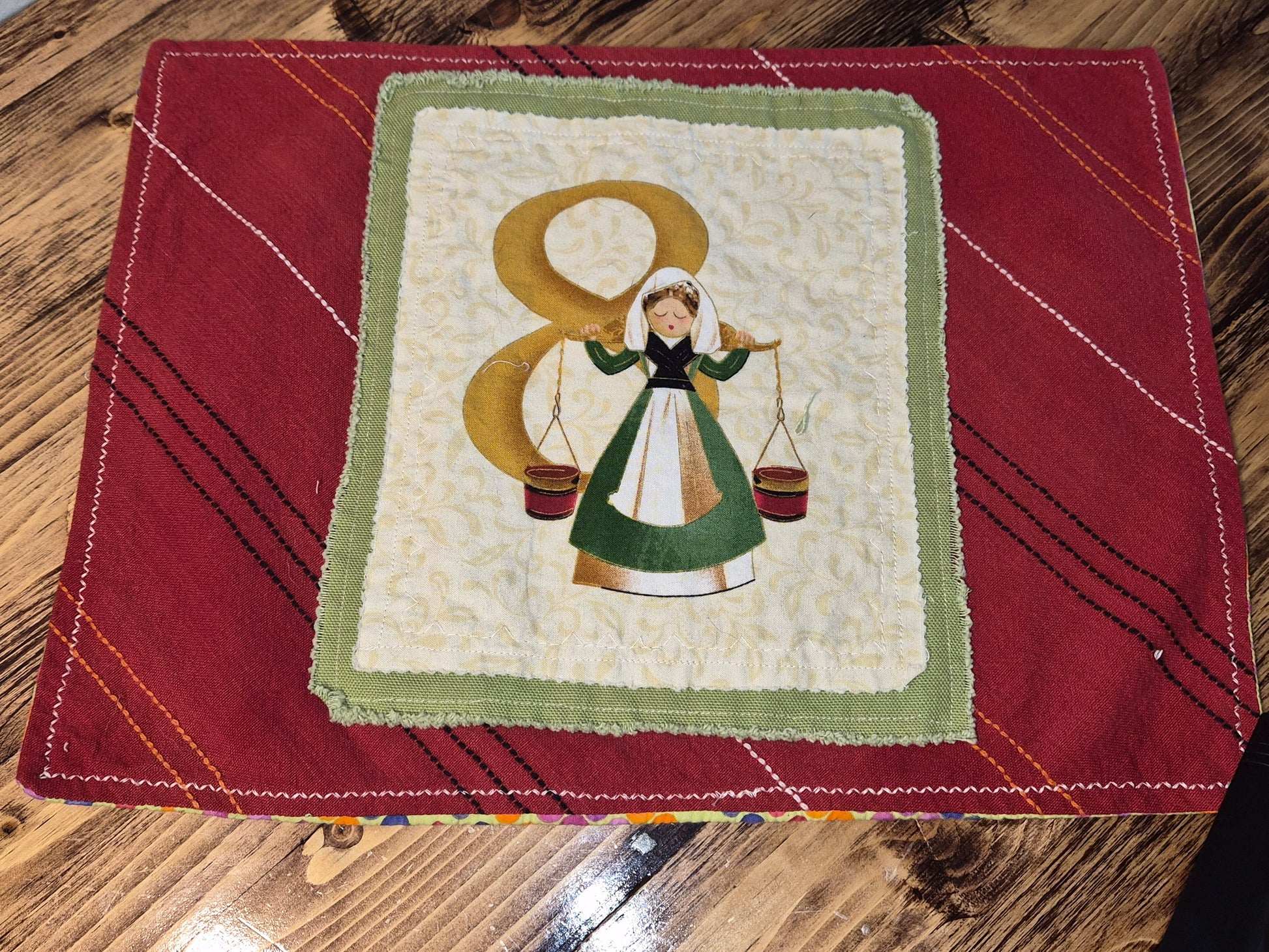 Patchwork quilted placemat with a woman and number 8 design on a red background