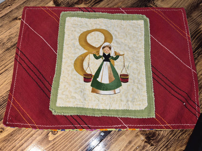 Patchwork quilted placemat with a woman and number 8 design on a red background