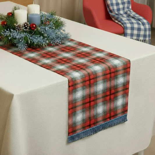 Red, white, grey, gold, and black tartan table runner on a white table with a Christmas centerpiece.